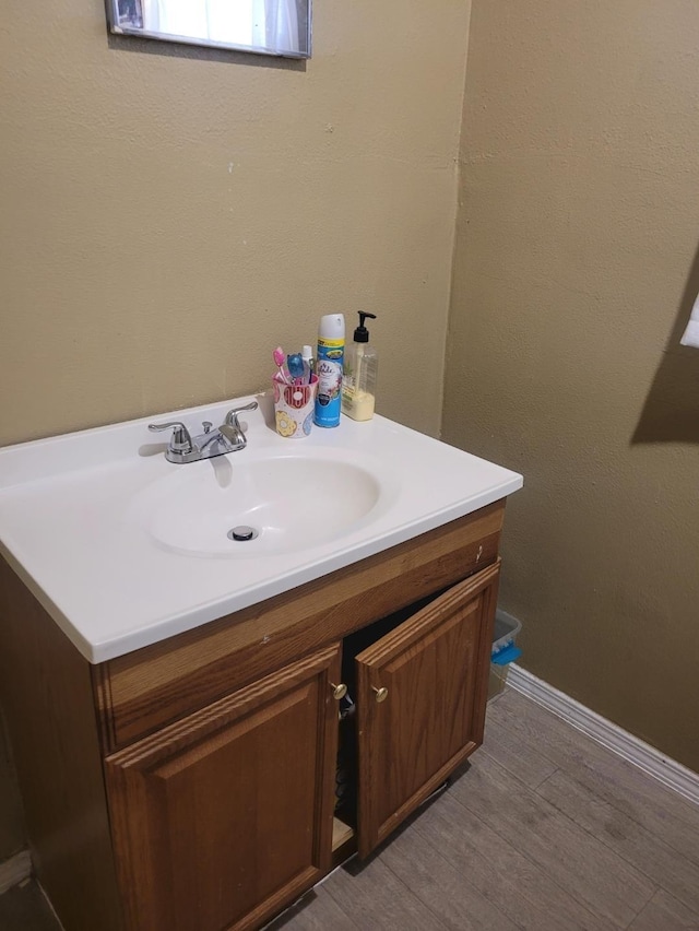 bathroom with wood finished floors, vanity, and baseboards