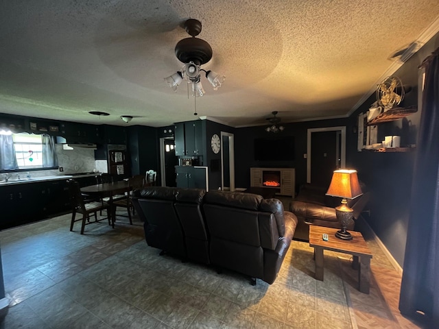 living room with ceiling fan, a fireplace, crown molding, and a textured ceiling