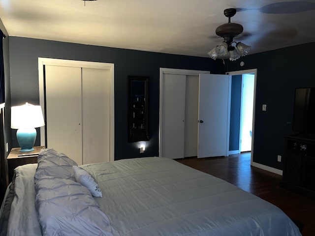 bedroom with ceiling fan, dark hardwood / wood-style floors, and two closets