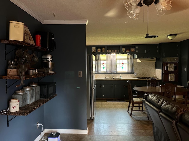 kitchen featuring stainless steel refrigerator, decorative backsplash, sink, and a textured ceiling