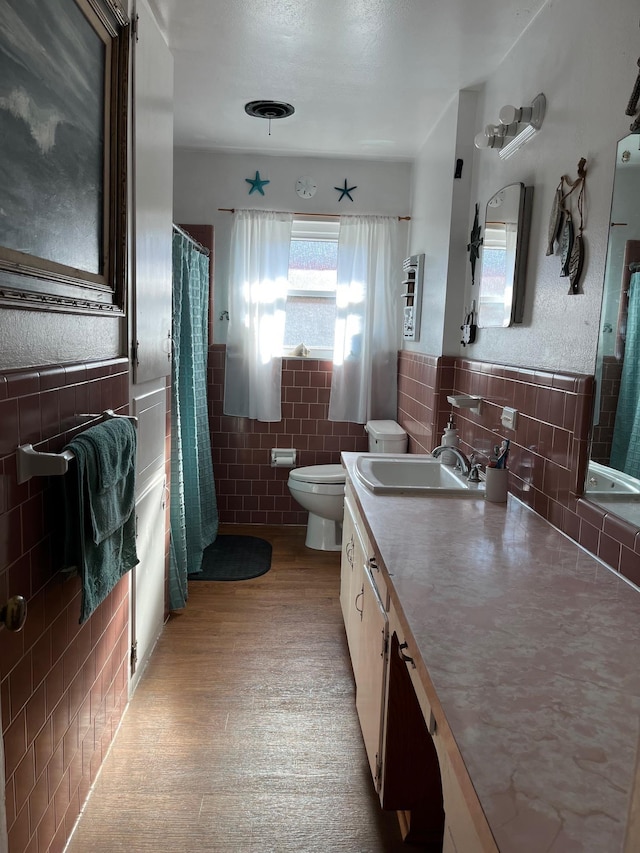 bathroom with hardwood / wood-style floors, vanity, tile walls, and toilet