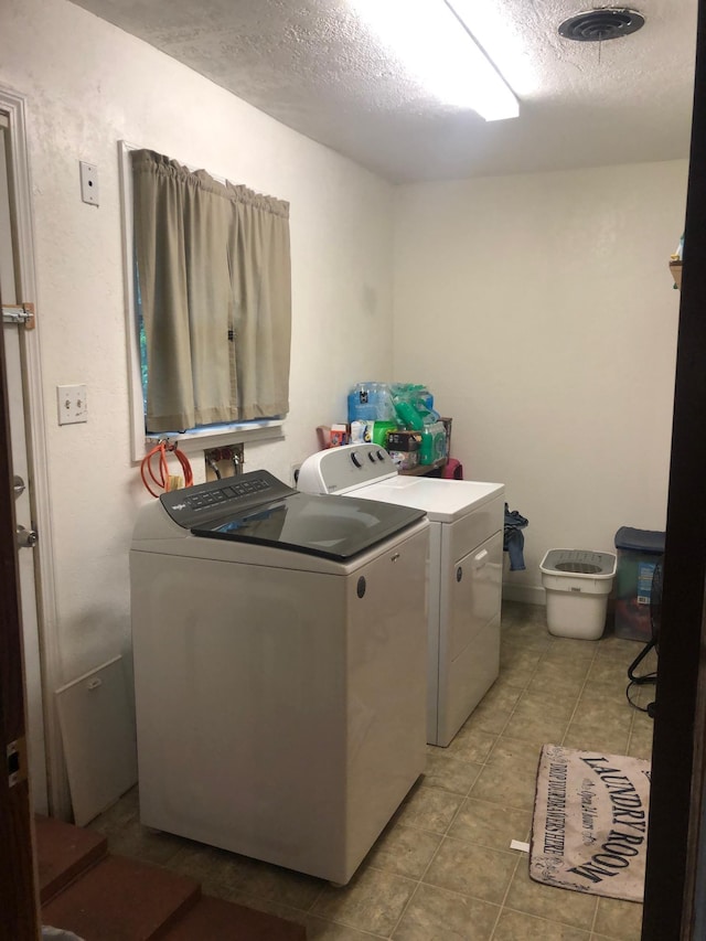 laundry area with washer and dryer and a textured ceiling