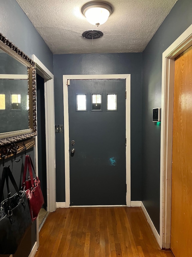 doorway with a textured ceiling and hardwood / wood-style flooring