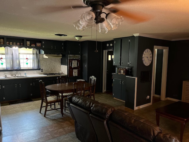 kitchen with decorative backsplash, a textured ceiling, stainless steel gas stovetop, and sink