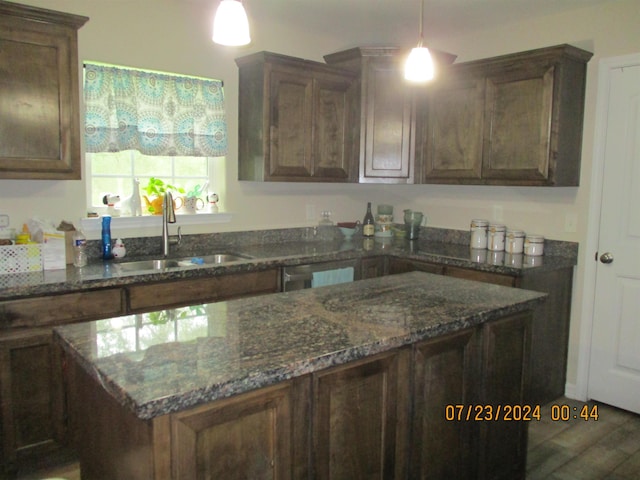 kitchen featuring dark stone countertops, dark brown cabinetry, sink, and pendant lighting