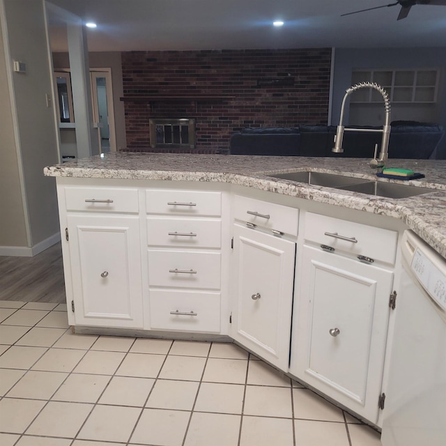 kitchen featuring sink, light tile patterned floors, dishwasher, ceiling fan, and white cabinets