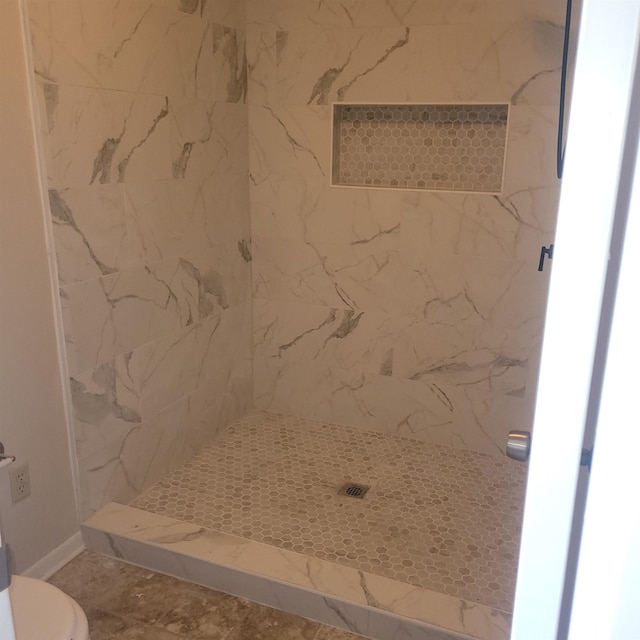 bathroom with a tile shower and toilet