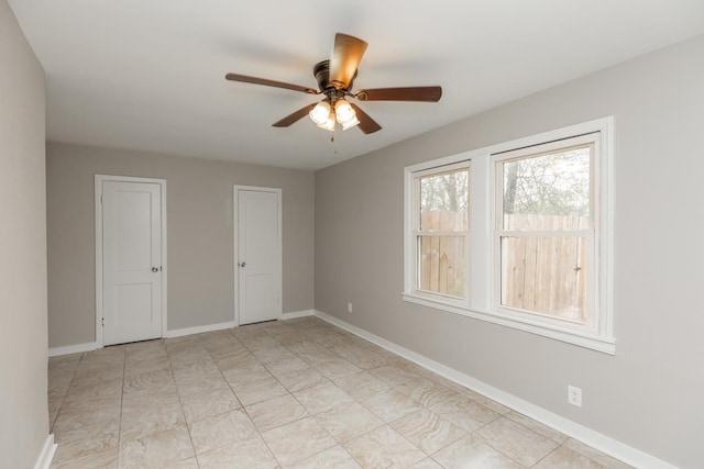 empty room with ceiling fan and baseboards