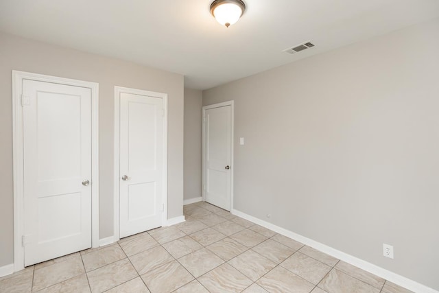 unfurnished bedroom with light tile patterned flooring, baseboards, and visible vents