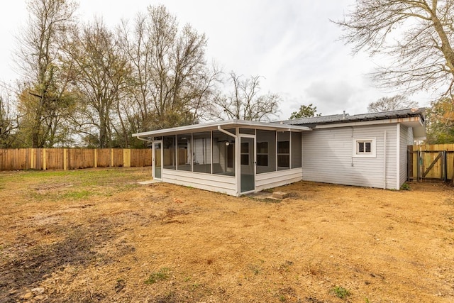 back of property featuring a fenced backyard and a sunroom