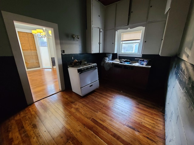 kitchen featuring hardwood / wood-style floors, an inviting chandelier, and gas range gas stove