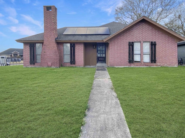 view of front of property with a front lawn and solar panels