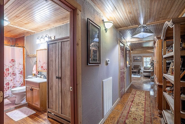 corridor featuring wooden walls, sink, and wooden ceiling