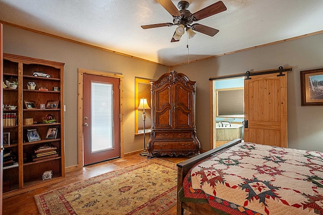 bedroom with a barn door, ceiling fan, a textured ceiling, and hardwood / wood-style flooring