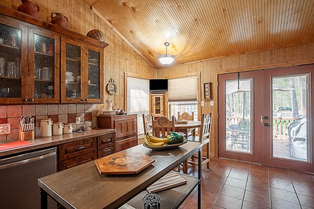 dining area with lofted ceiling, french doors, dark tile patterned flooring, wooden walls, and wood ceiling