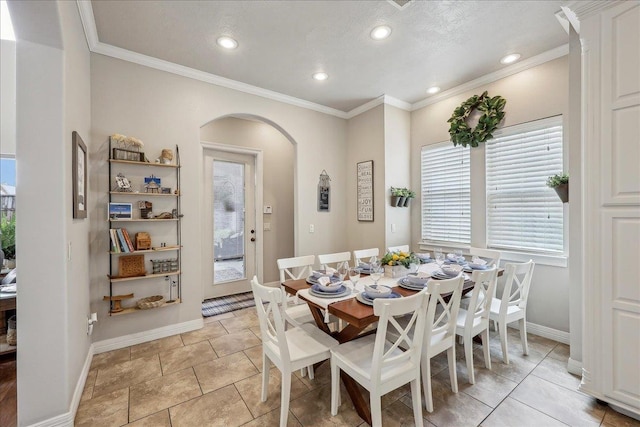 dining room featuring arched walkways, ornamental molding, baseboards, and recessed lighting
