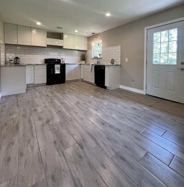 kitchen featuring decorative backsplash, black appliances, light hardwood / wood-style floors, white cabinetry, and hanging light fixtures