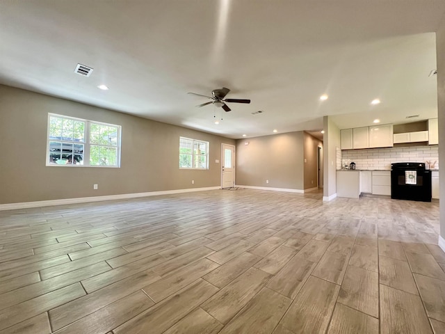 unfurnished living room with ceiling fan and a healthy amount of sunlight