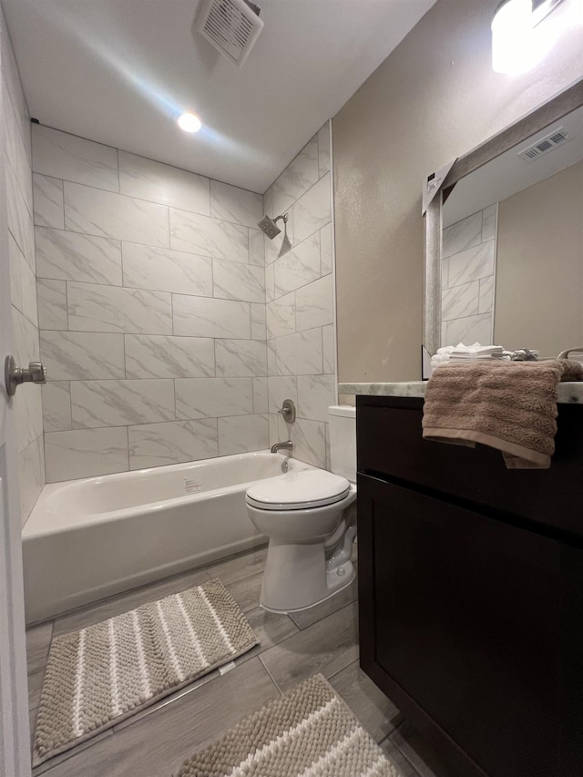 full bathroom with toilet, vanity, and tiled shower / bath