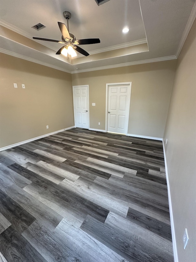 empty room with dark hardwood / wood-style floors, a raised ceiling, ceiling fan, and ornamental molding