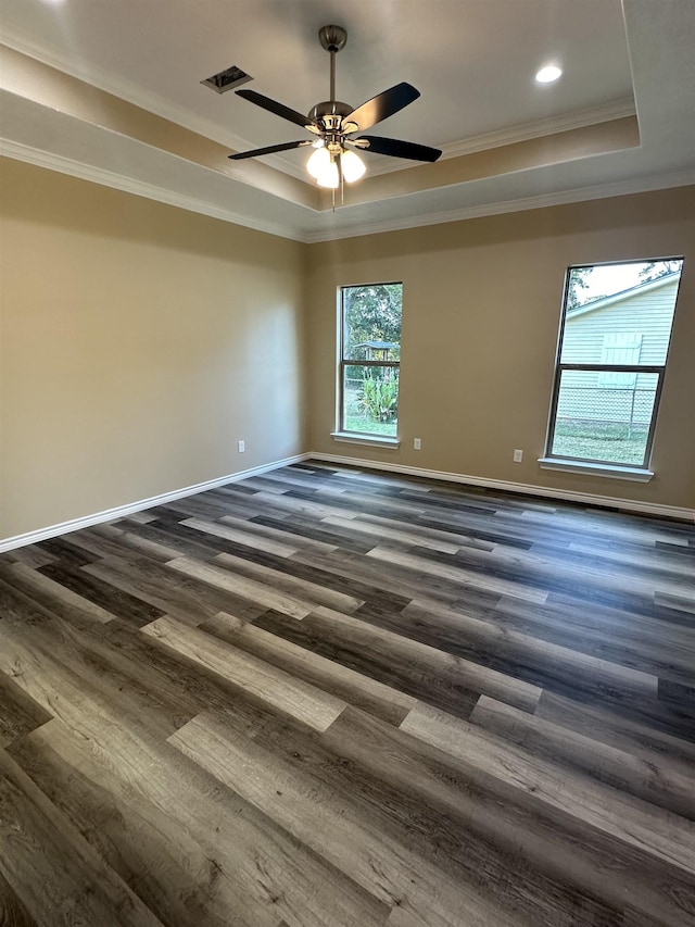 unfurnished room featuring a healthy amount of sunlight, dark hardwood / wood-style flooring, and a tray ceiling