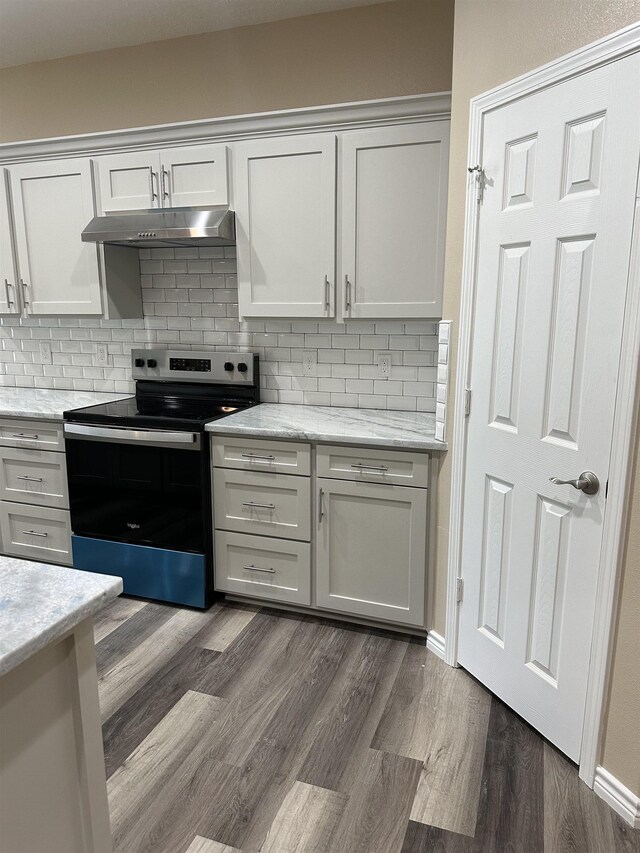 kitchen with tasteful backsplash, electric stove, light stone counters, and dark hardwood / wood-style flooring