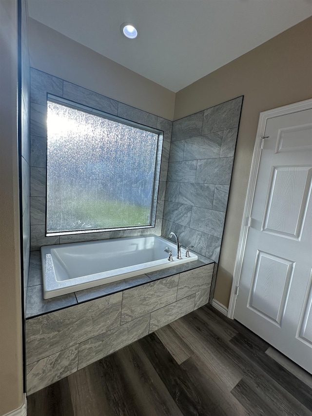 bathroom featuring wood-type flooring and tiled bath