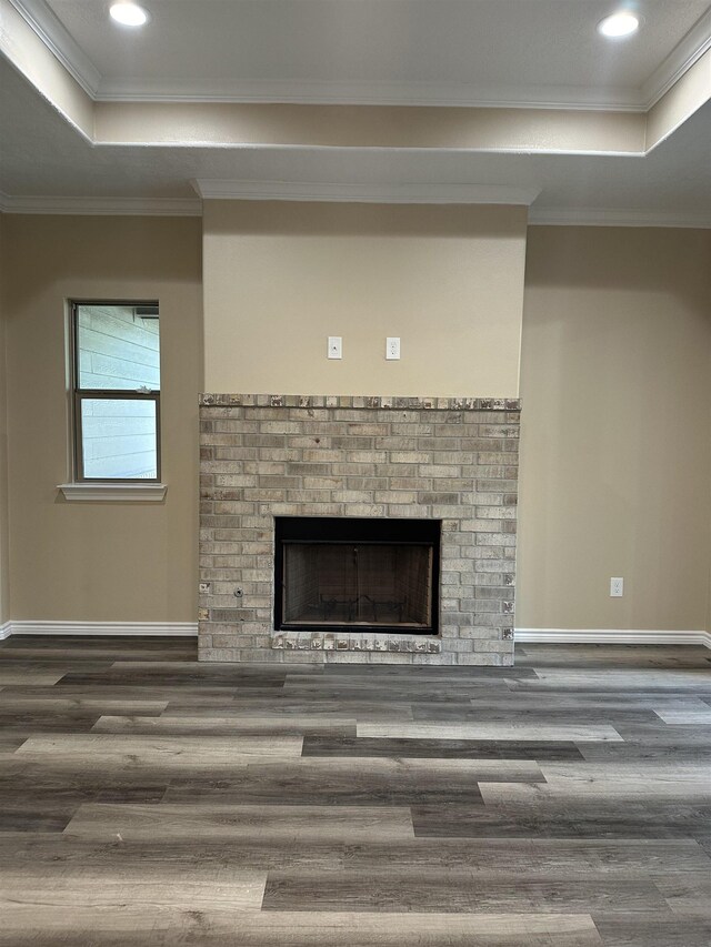 room details with a brick fireplace, wood-type flooring, ornamental molding, and a tray ceiling