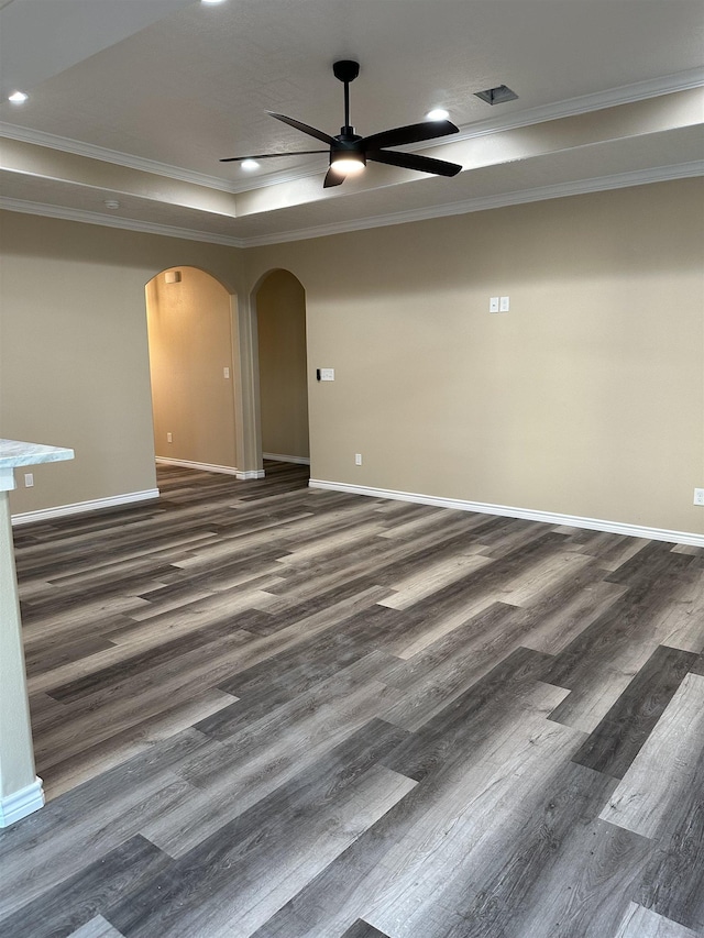 spare room featuring a raised ceiling, ceiling fan, dark hardwood / wood-style flooring, and ornamental molding