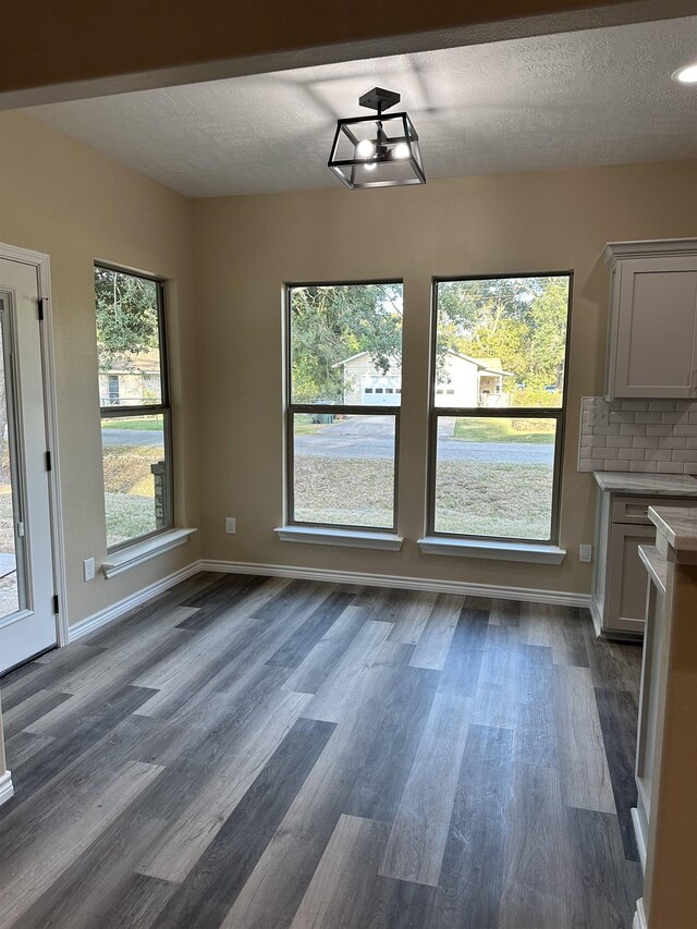 unfurnished dining area featuring dark wood-type flooring and a textured ceiling