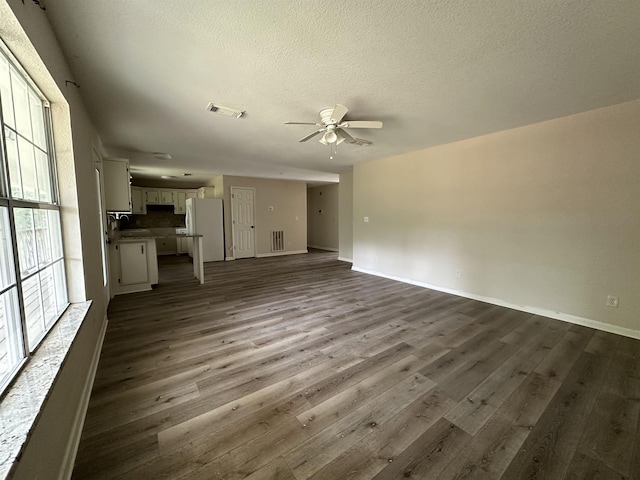 unfurnished living room featuring ceiling fan, sink, dark wood-type flooring, and a textured ceiling