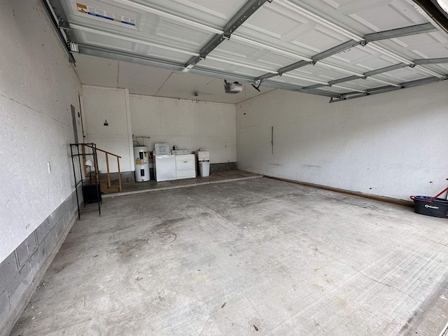 garage with water heater, a garage door opener, and washing machine and clothes dryer