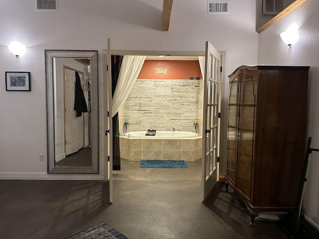 bathroom with tiled bath, lofted ceiling with beams, and concrete flooring