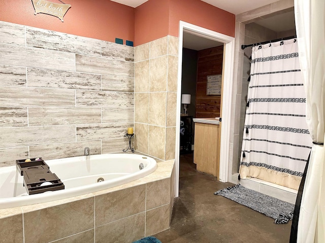 bathroom with concrete flooring and tiled bath