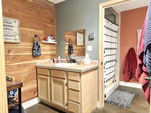 bathroom with a shower with curtain, vanity, concrete flooring, and wooden walls