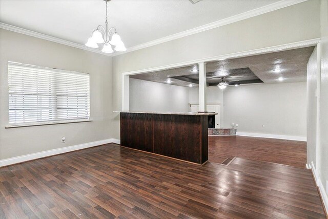 interior space featuring pendant lighting, ceiling fan with notable chandelier, dark hardwood / wood-style floors, ornamental molding, and kitchen peninsula