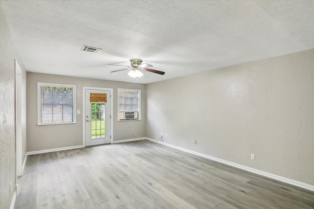 unfurnished room with ceiling fan, light hardwood / wood-style floors, a textured ceiling, and cooling unit