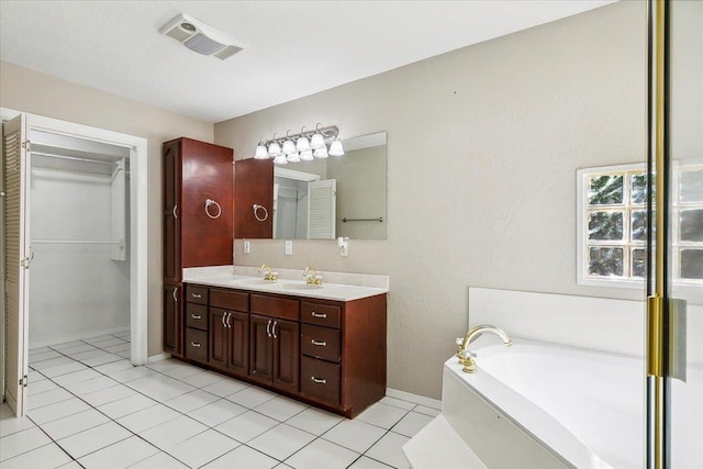 bathroom with tile patterned floors, a tub, and vanity