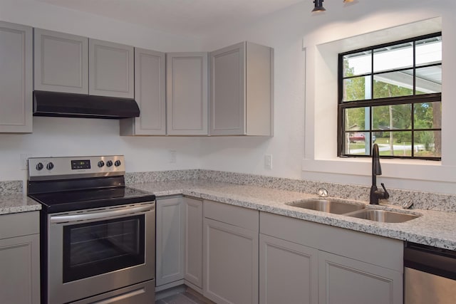 kitchen with appliances with stainless steel finishes, light stone counters, gray cabinetry, and sink