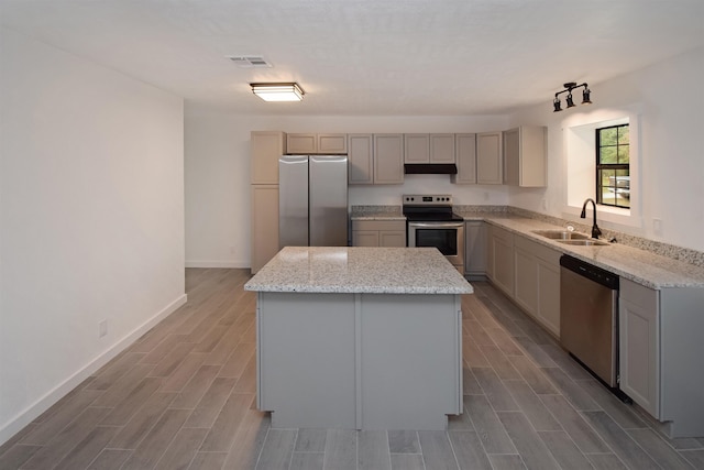 kitchen featuring gray cabinetry, sink, a kitchen island, light stone counters, and stainless steel appliances