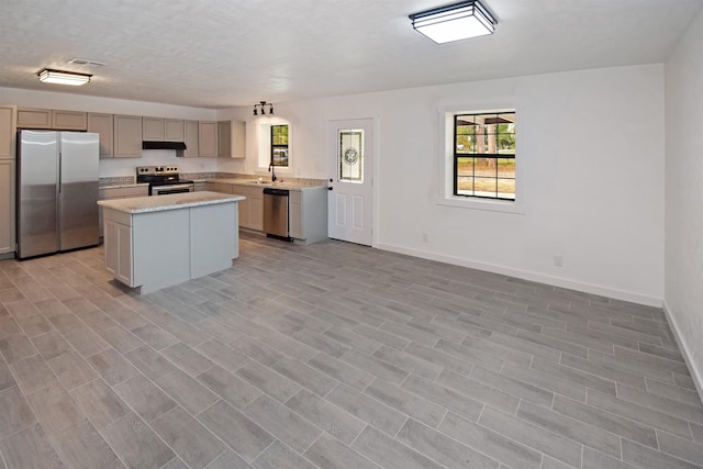 kitchen featuring a kitchen island, sink, light stone countertops, and stainless steel appliances