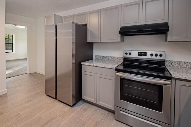 kitchen with gray cabinets, light stone counters, light colored carpet, and appliances with stainless steel finishes