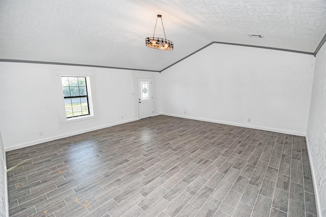 interior space with a textured ceiling, vaulted ceiling, ornamental molding, and a notable chandelier