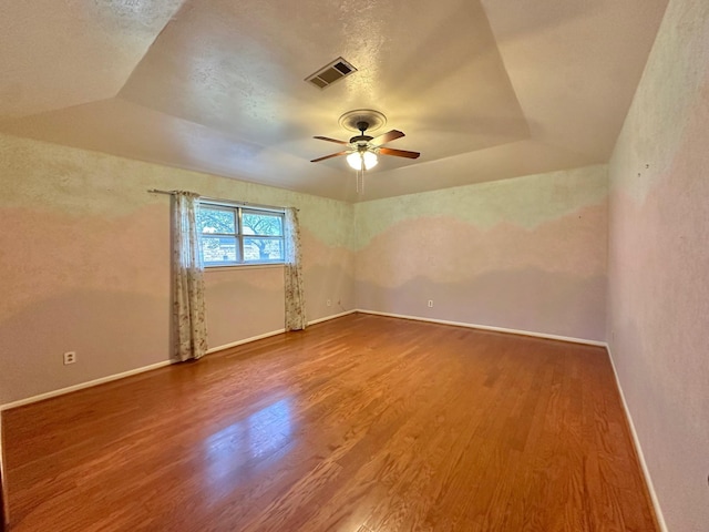 spare room featuring a tray ceiling, ceiling fan, a textured ceiling, and hardwood / wood-style flooring