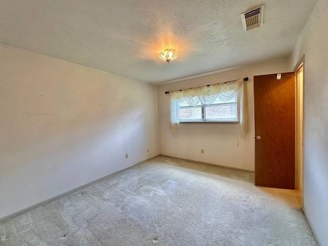 spare room featuring light carpet and a textured ceiling