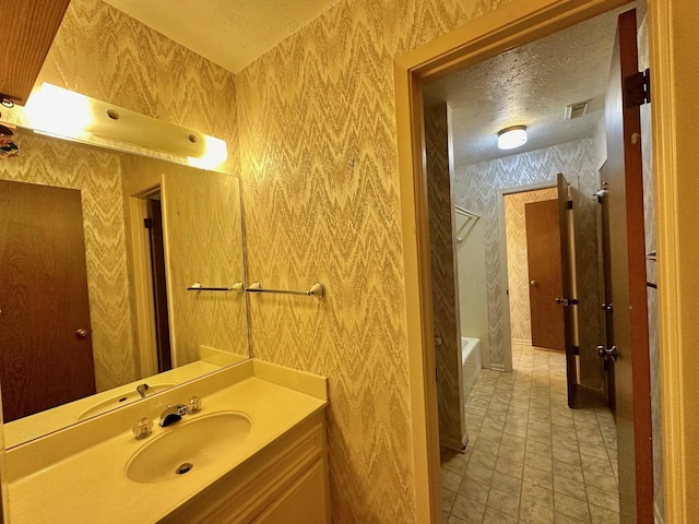 bathroom featuring vanity, a bathtub, and a textured ceiling