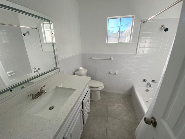 full bathroom featuring vanity, tiled shower / bath, tile patterned flooring, toilet, and tile walls