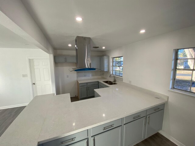 kitchen featuring sink, dark hardwood / wood-style floors, gray cabinets, range hood, and kitchen peninsula