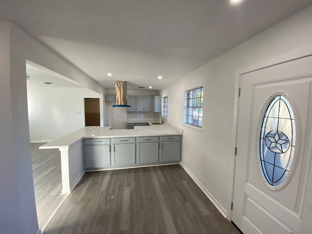 kitchen featuring dark wood-type flooring, sink, wall chimney exhaust hood, gray cabinets, and kitchen peninsula