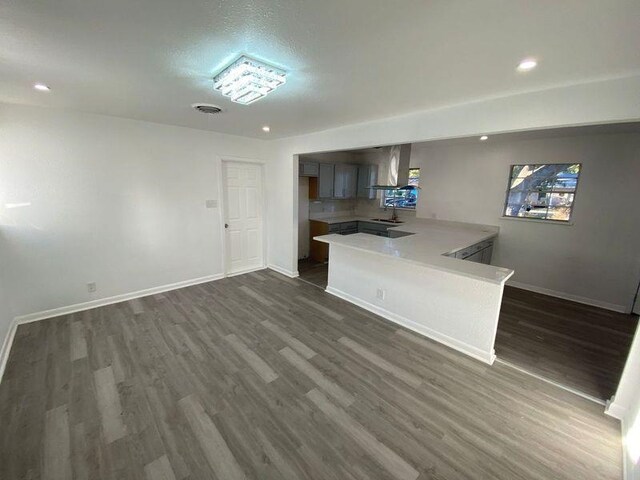 kitchen with kitchen peninsula, exhaust hood, and dark hardwood / wood-style floors